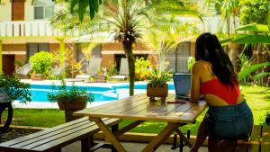 a woman sitting at a picnic table with a laptop at Casa Losodeli & Coworking- Adults Only in Puerto Escondido