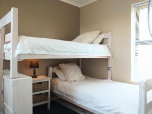 two bunk beds in a room with a lamp at Little Greece - Beach House Apartment by Mykonos in Langebaan