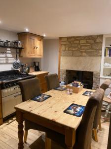 a kitchen with a wooden table with chairs and a fireplace at Spaniel Cottage with views of Ham hill, Stoke sub Hamdon in Martock