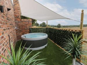 a hot tub in a garden under a white umbrella at Slitting Mill Annex in Rugeley