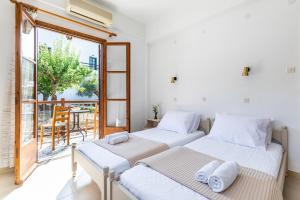 two beds in a room with a balcony at Skopelos Evergreen Apartments in Stafylos