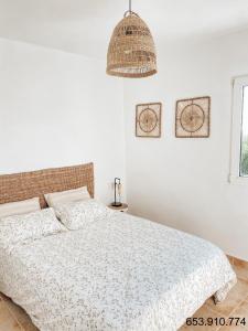 ein weißes Schlafzimmer mit einem Bett und einem hängenden Licht in der Unterkunft Montgo Home in Jávea