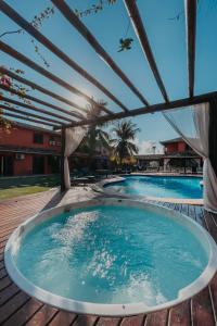 a hot tub under a pergola next to a swimming pool at Pousada Sabledor in Búzios