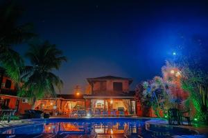 a swimming pool in front of a house at night at Pousada Sabledor in Búzios