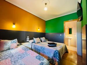 twee bedden in een kamer met groene en gele muren bij Hostal Numancia in Madrid