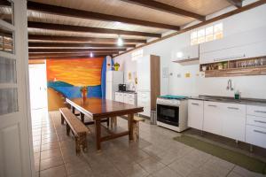 uma cozinha com uma mesa de madeira e uma cozinha com armários brancos em Hostel Butiá em Laguna