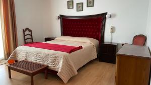 1 dormitorio con 1 cama con cabecero rojo y mesa en Pensao Vista Bela, en Miranda do Douro