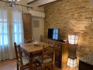 a dining room with a wooden table and a television at Casa Rural Valle del Palancia in Castellnovo
