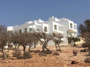 un grande edificio bianco con alberi di fronte di Duplex Taghazout Ocean with pool & fitness a Taghazout