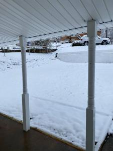 een met sneeuw bedekte veranda met een wit dak bij Country Comfy Right in Town in Charleston