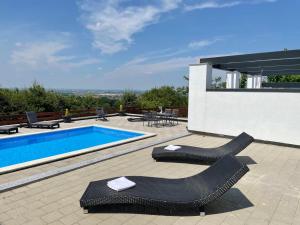 a swimming pool with two black chairs next to a building at Relax zone - Apartmani La ISA in Varaždin Breg