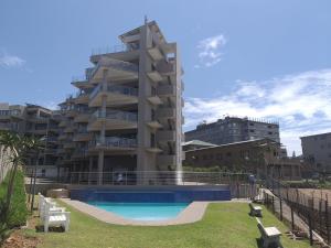 a building with a swimming pool in front of a building at Whale Rock, Modern Beachfront Apartment in Margate