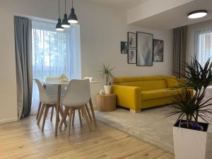 a living room with a yellow couch and a table and chairs at ARMERIA 4/1 in Štrbské Pleso