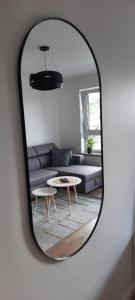 a mirror reflecting a living room with a couch and a table at Apartament Nel in Zielona Góra