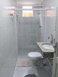 a bathroom with a shower and a toilet and a sink at Casa Aconchego Guarujá in Guarujá