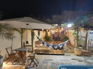 a hammock on a patio with a table and chairs at Brotas Suítes Belo Quinto in Brotas