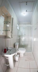 a white bathroom with a sink and a toilet at Casas do Preto in Guarda do Embaú