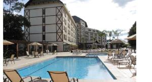 una gran piscina con sillas y un edificio en Cond Vista Azul Hotel, en Pedra Azul