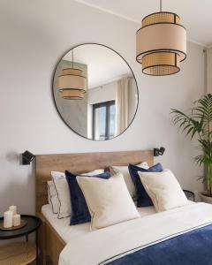 a bedroom with a large mirror above a bed with blue pillows at Apartament MorSky Gardenia Dziwnów in Dziwnów