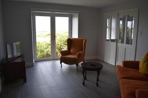 uma sala de estar com um sofá, uma cadeira e uma mesa em Aran View Holiday Home em Doolin