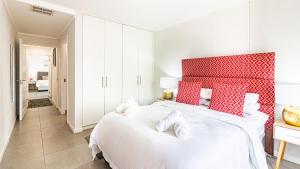 a bedroom with a large white bed with a red headboard at East Point in Durban