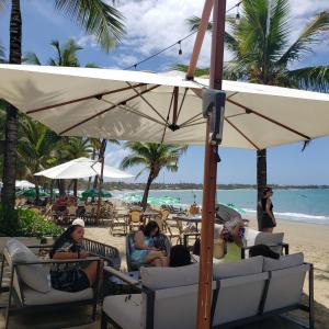 eine Gruppe von Menschen, die unter einem Sonnenschirm am Strand sitzen in der Unterkunft Lovely location , right downtown Puerto Plata in San Felipe de Puerto Plata