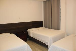 a room with two beds with white sheets at DC Suites Aeropuerto in Guayaquil