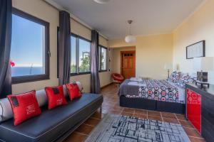 een slaapkamer met een bed, een bank en ramen bij Villa Tabua in Ribeira Brava