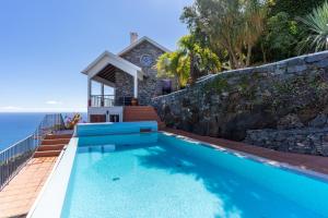 a house with a swimming pool next to the ocean at Villa Tabua in Ribeira Brava