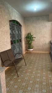 Hostel Assis Divinópolis في ديفينوبوليس: غرفة بها كرسي وزرع الفخار