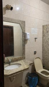 bagno con lavandino, servizi igienici e specchio di Hostel Assis Divinópolis a Divinópolis