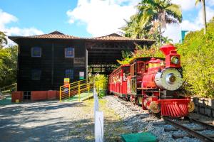 a red train on the tracks in front of a building at Hotel Dan Inn Poços de Caldas - A melhor localização do Centro in Poços de Caldas