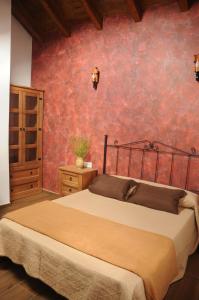 - une chambre avec un lit et un mur rouge dans l'établissement EL VASALLO 2, à Tragacete