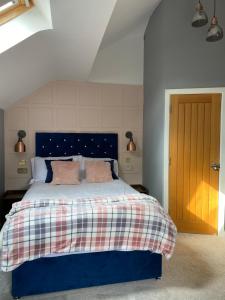a bedroom with a blue bed with pink pillows at Stratford House in Stratford-upon-Avon