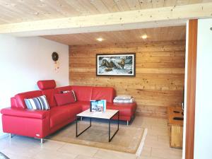 a living room with a red couch and a table at Chalet Enzian in Riederalp