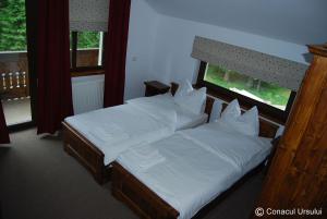 a bedroom with two beds with white sheets and a window at Conacul Ursului in Cumpăna +26 photos