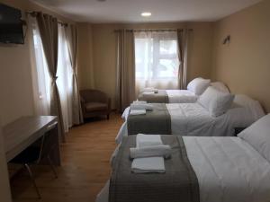 Habitación de hotel con 4 camas y toallas. en Gran Hotel Aysen, en Puerto Aysén