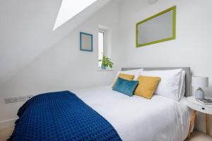 a bedroom with a white bed with blue and yellow pillows at Bells Chapel - Bright Rooftop Apartment in the Centre of Town with Juliet Balconies in Falmouth