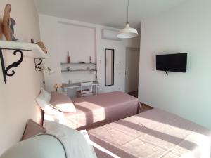 een witte kamer met 2 bedden en een televisie bij LORA GIUSTA GUEST HOUSE in Como