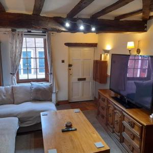 a living room with a couch and a large television at Cosy Georgian Cottage in the Heart of Bewdley, Worcestershire in Bewdley