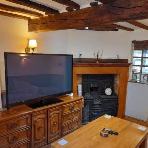 uma grande televisão de ecrã plano num centro de entretenimento em madeira em Cosy Georgian Cottage in the Heart of Bewdley, Worcestershire em Bewdley
