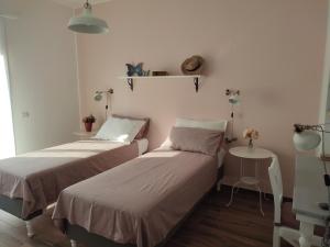 two beds in a small room with a table at LORA GIUSTA GUEST HOUSE in Como