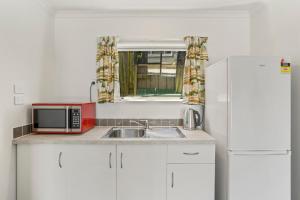 a kitchen with a sink and a microwave and a refrigerator at Karori Kabin - Karori Holiday Home in Wellington +6 photos
