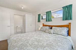 a bedroom with a large bed with green curtains at Karori Kabin - Karori Holiday Home in Wellington