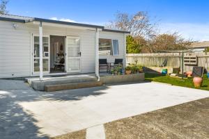 a small white house with a patio at Karori Kabin - Karori Holiday Home in Wellington