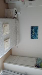 Habitación blanca pequeña con cama y una foto en la pared en Juana I en Villa Elisa