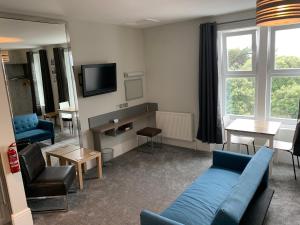 a living room with a couch and chairs and a tv at Harmony Apartments in Weston-super-Mare