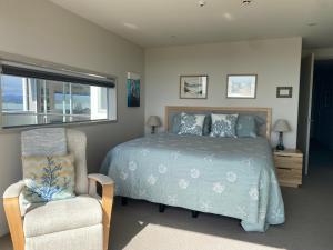 a bedroom with a bed and a chair and a window at Ohope Beach Resort in Ohope Beach +40 photos