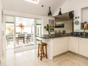 a kitchen with white cabinets and a counter with a table at Ridgeback House in Helston