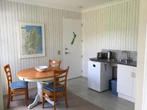 eine Küche mit einem Tisch und Stühlen sowie einem Kühlschrank in der Unterkunft Abel Tasman Sands BnB in Marahau